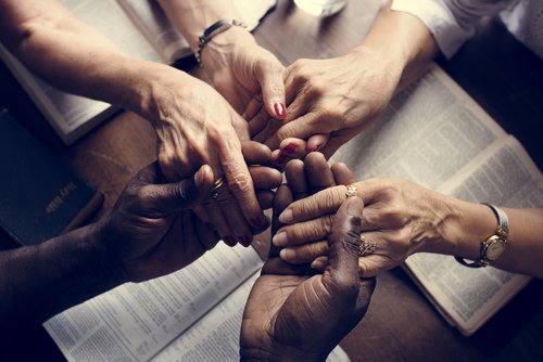 A group of people holding hands and praying