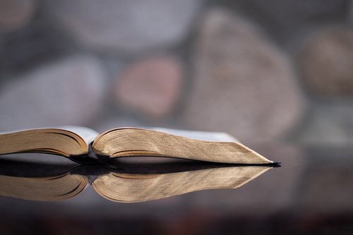 An open Bible on a table with reflection